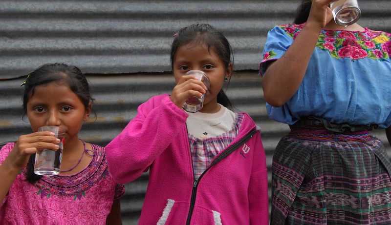 Girls in Guatemala drinking safe water from Climate Impact Partners' Ecofiltro safe water project